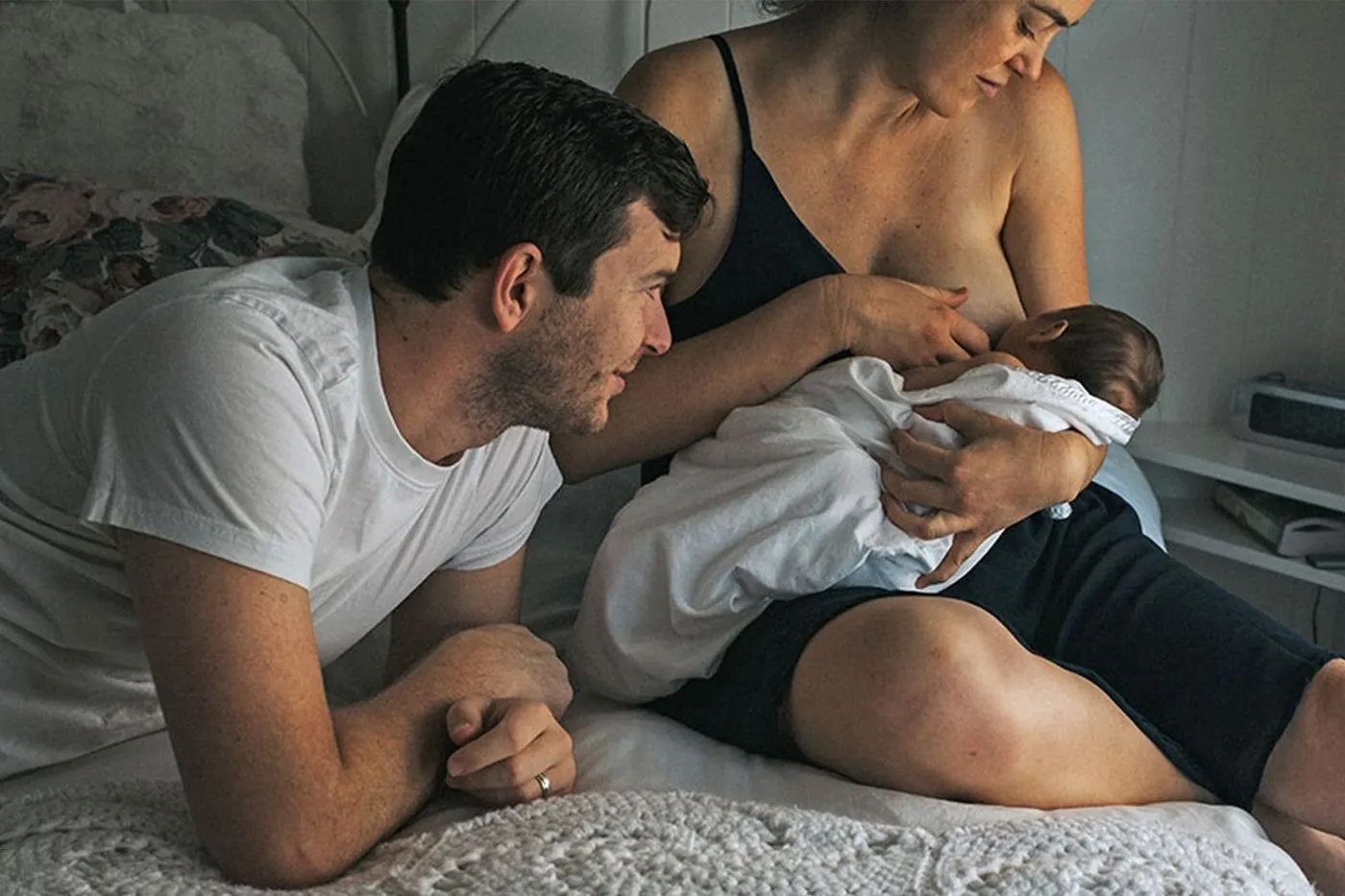 Mother holding a newborn baby wrapped in a soft blanket near a bright window