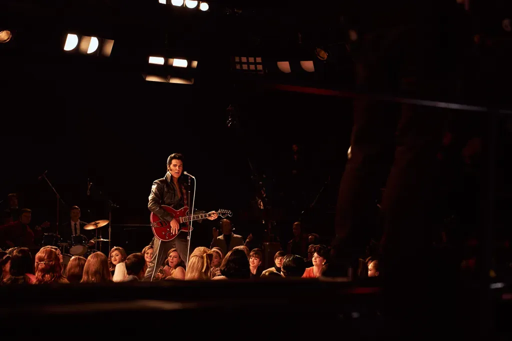Elvis Presley performing energetically on stage with guitar during early rockabilly-era inspired scenes