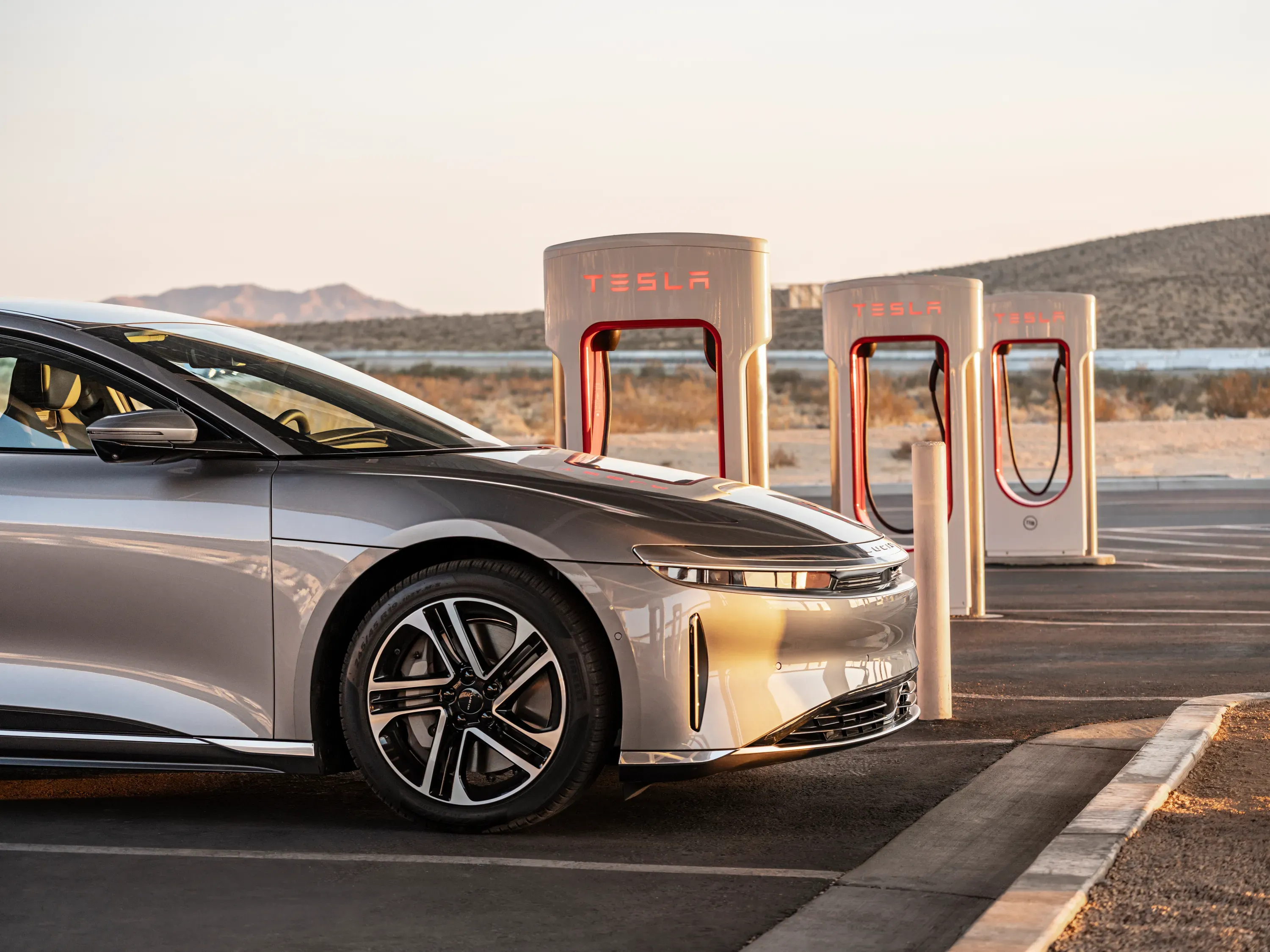 Lucid Air connected to a Tesla Supercharger via NACS adapter, representing expanded EV charging access