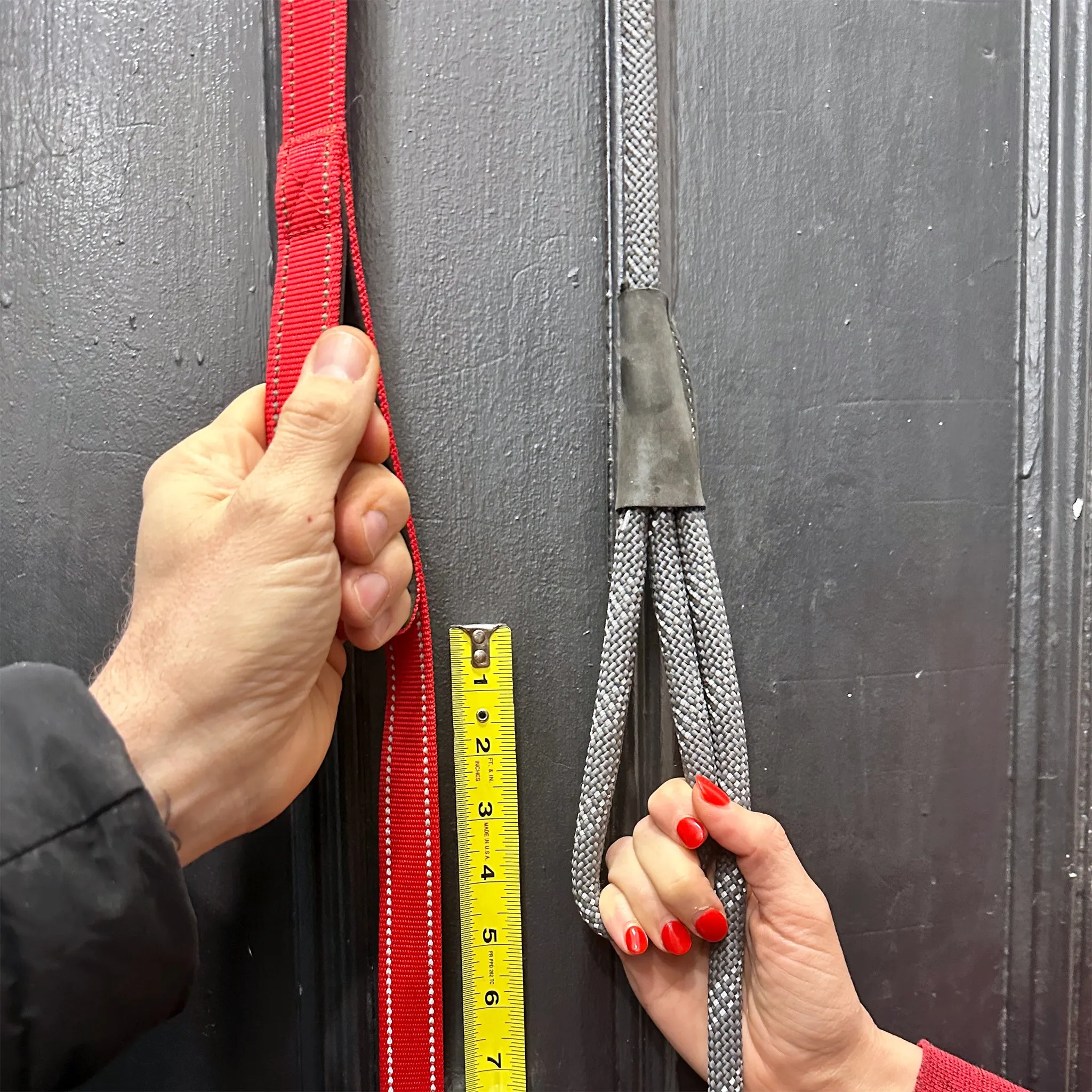 Two hands holding two different dual-handle leashes side by side, showing the difference in traffic handle distance from the clip