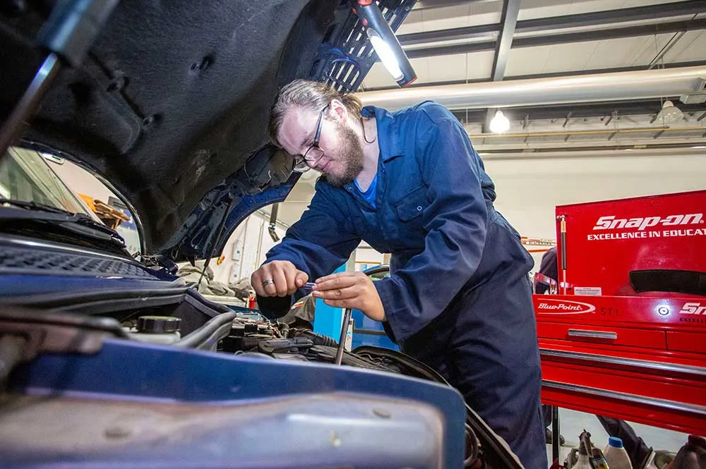 Mechanic inspecting a vehicle engine bay during hands-on diagnostic training session