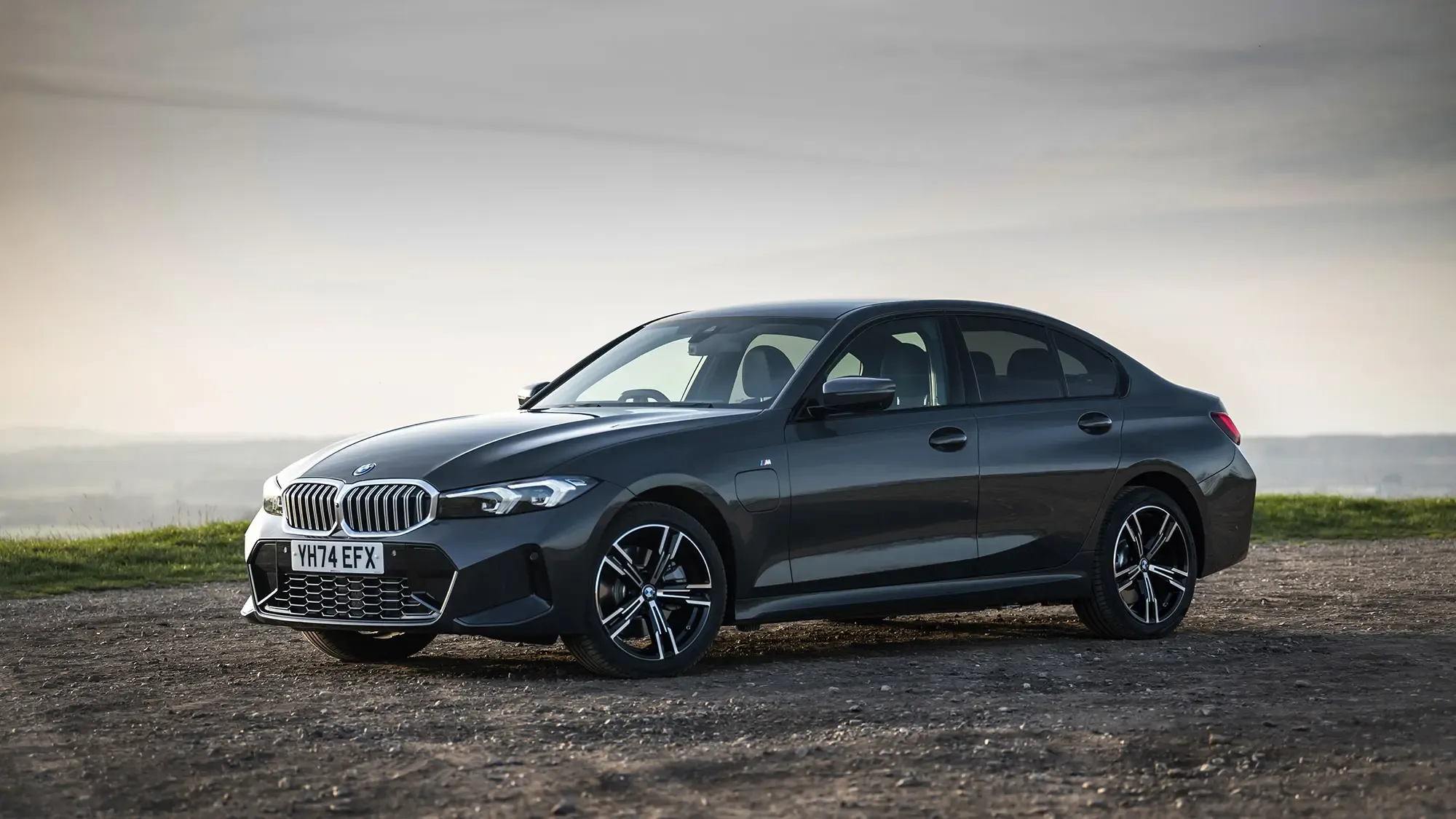 BMW 330e (2024) front three quarter static view in grey paint