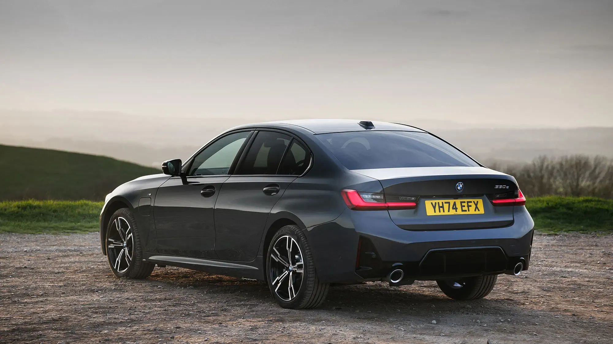 BMW 330e (2024) rear three quarter static in grey, showing boot and tail lamp design