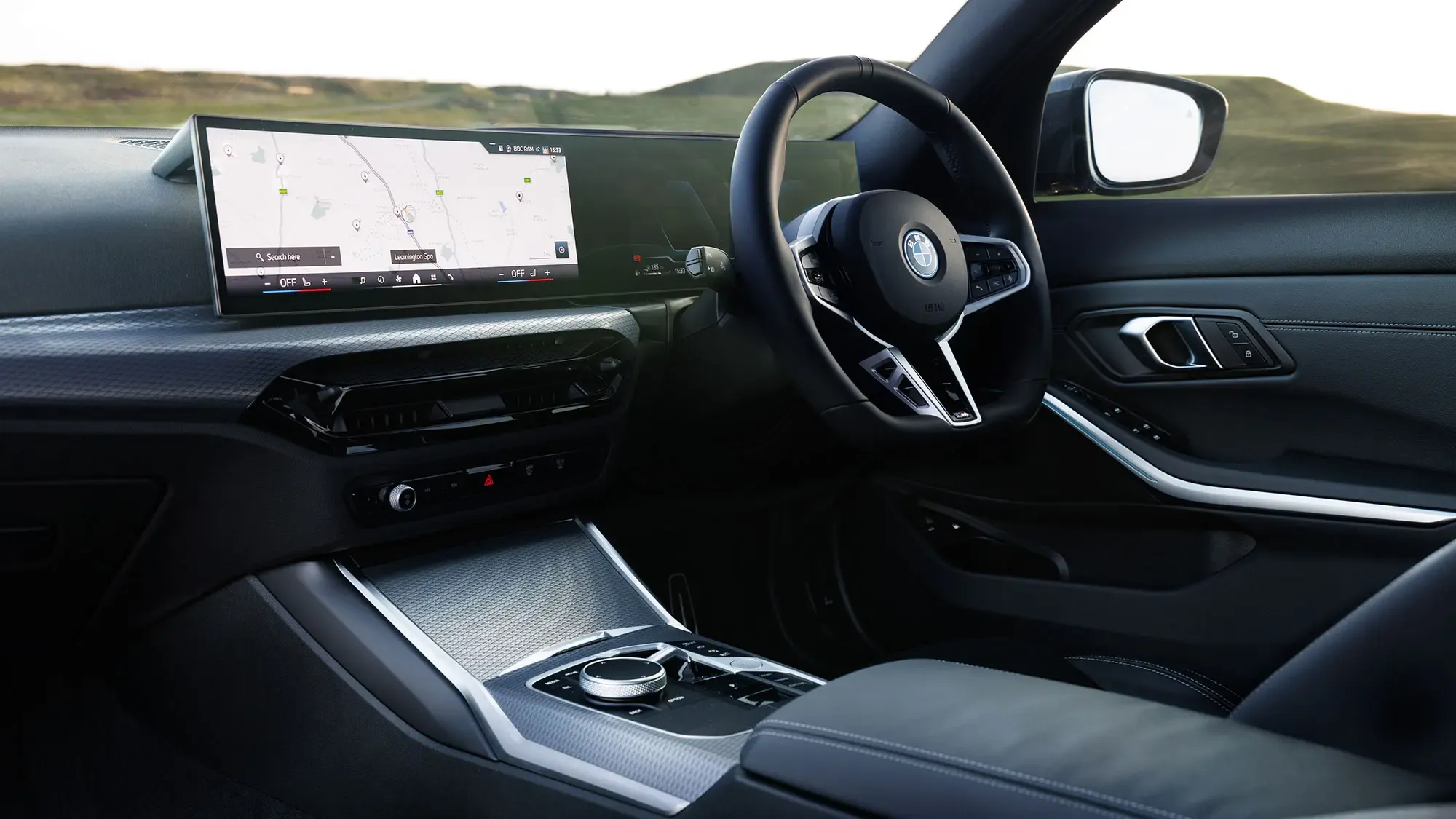 BMW 330e (2024) dashboard and iDrive infotainment system with black leather upholstery
