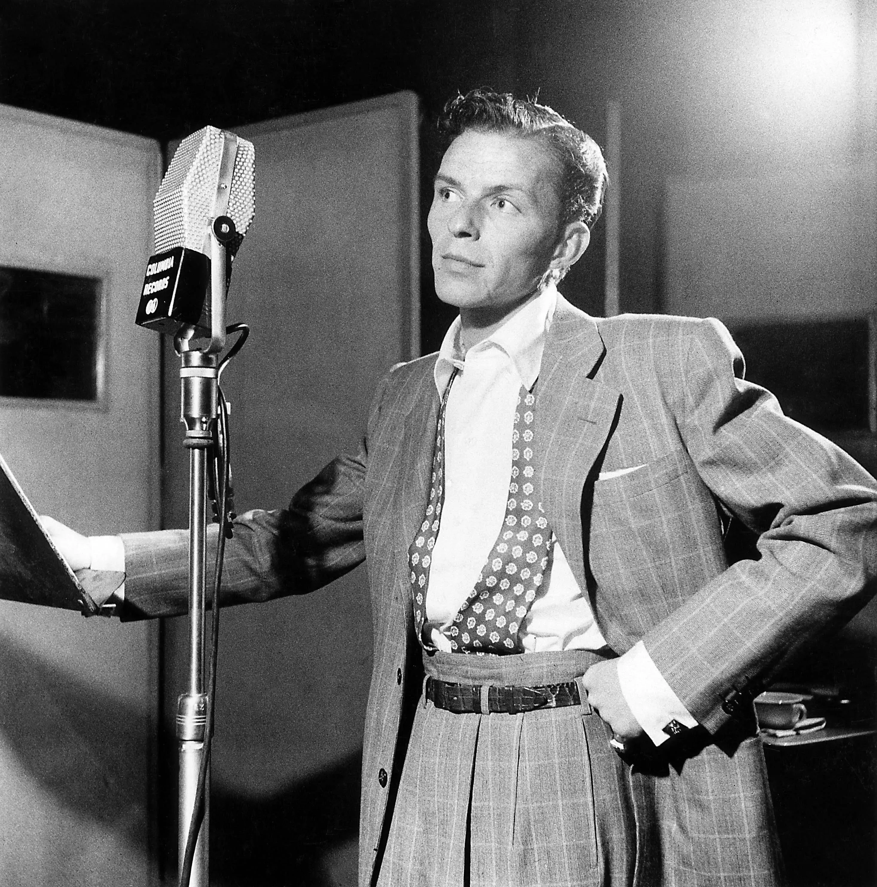 Photo of Frank Sinatra posing next to a microphone at Columbia Recording studios