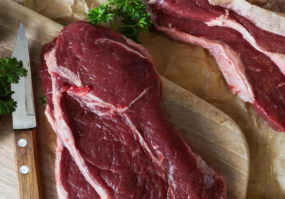 A dog owner preparing raw chicken and beef portions for a balanced canine diet