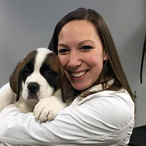 Veterinary student holding a young puppy during a wellness check