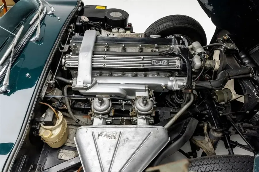 Jaguar E-Type 4.2-liter inline-six engine with twin SU carburetors visible under the hood