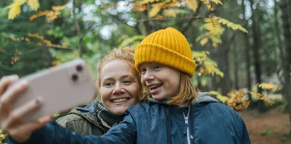 Mother and daughter taking a photo on a hike, smiling together outdoors