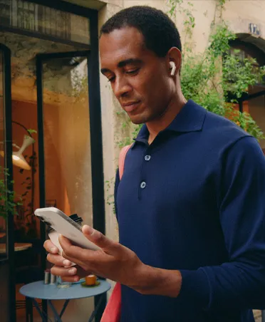 Person on a city street looking at their iPhone, maintaining seamless Wi-Fi connection across network transfers