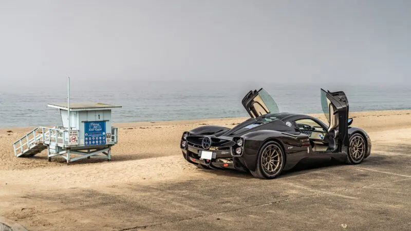 Pagani Utopia with gull-wing doors open near a beach