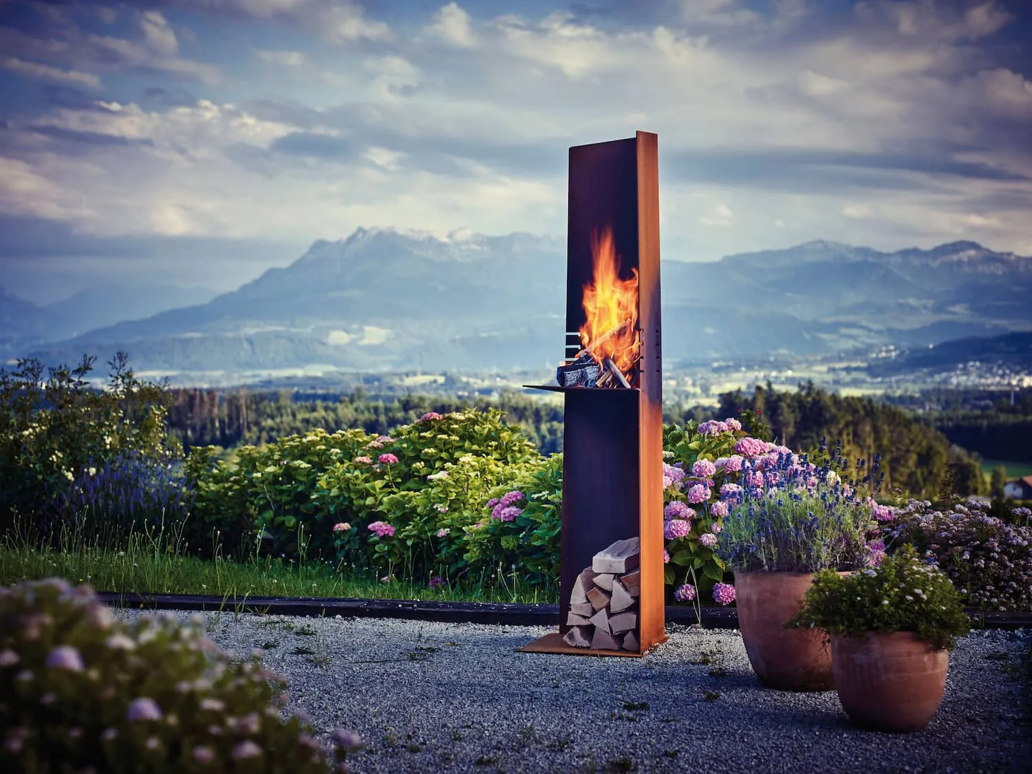 Angle outdoor fire pit made from weathered Corten steel creating a sculptural garden focal point
