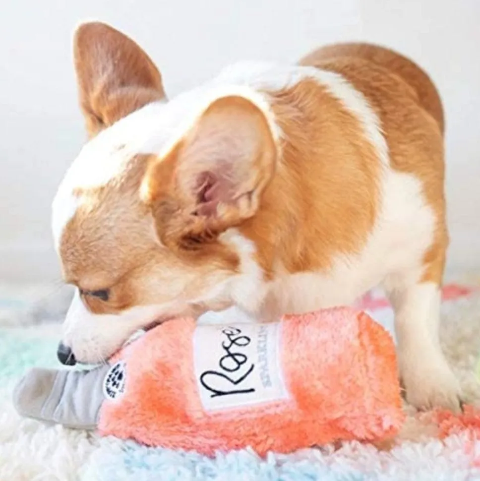 Dog chewing on the pink rosé bottle dog toy