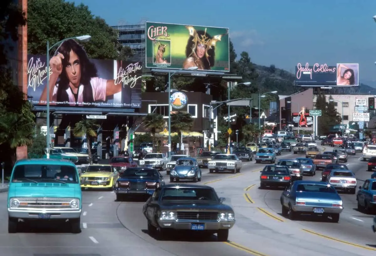 Cars moving along Sunset Strip under vintage billboards in Los Angeles traffic scene