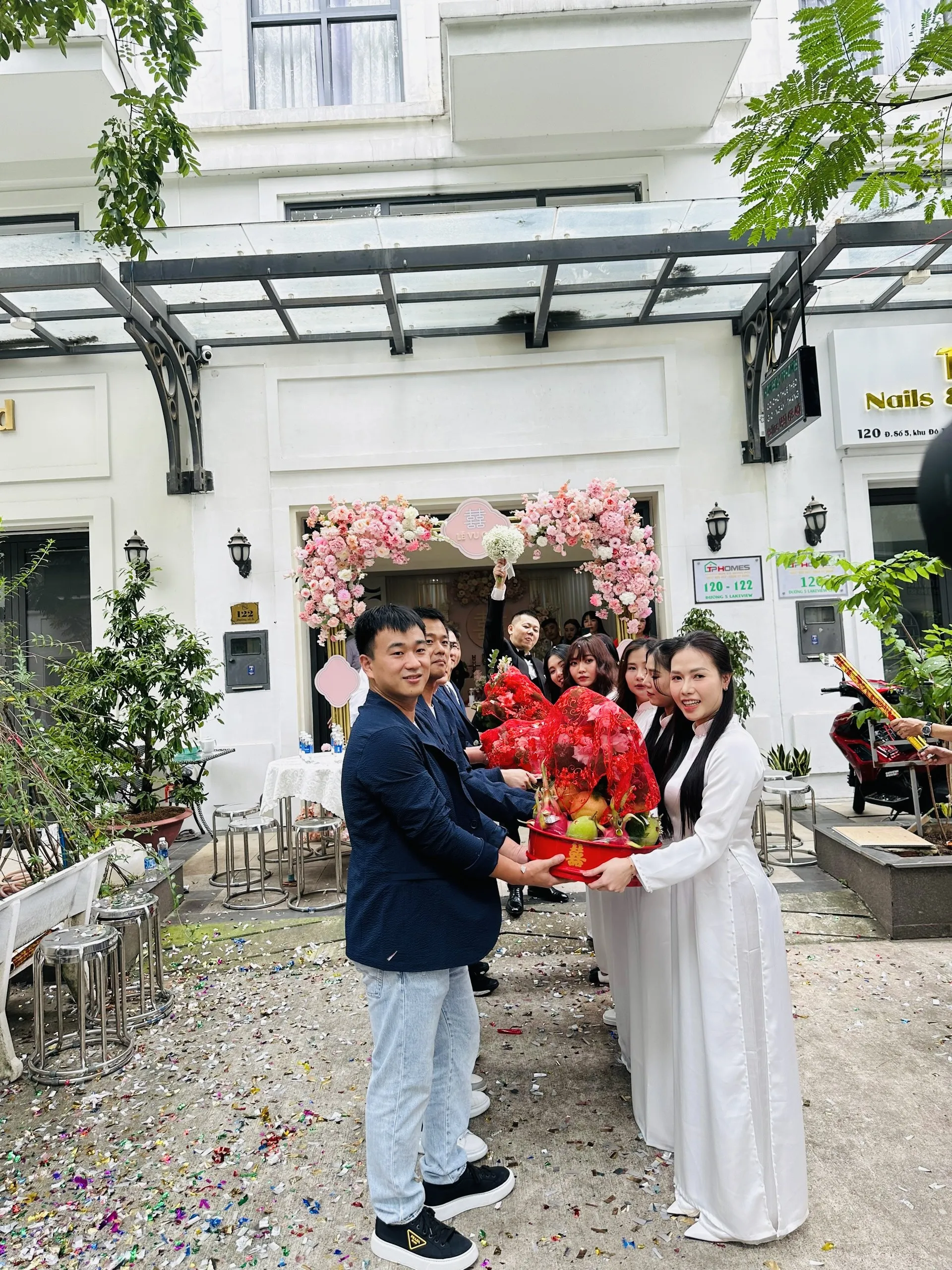 Couple and bridal entourage captured in front of luxury wedding vehicles
