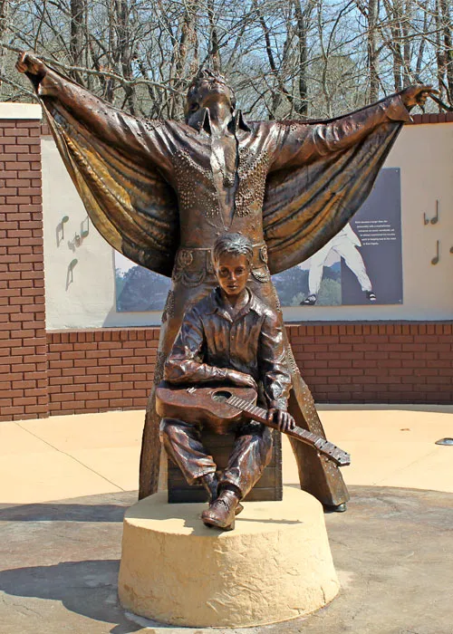 Two symbolic statues representing Elvis' journey from childhood dreamer to legendary performer