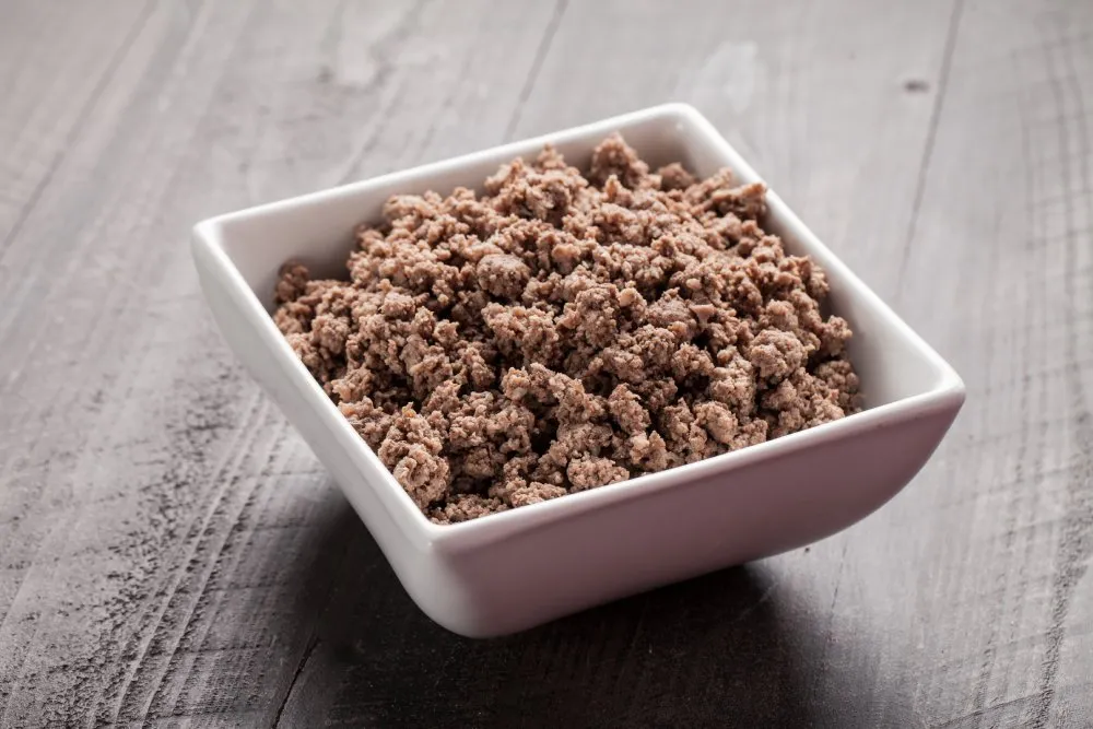 Cooked lean meat portioned in a bowl as part of a homemade dog meal