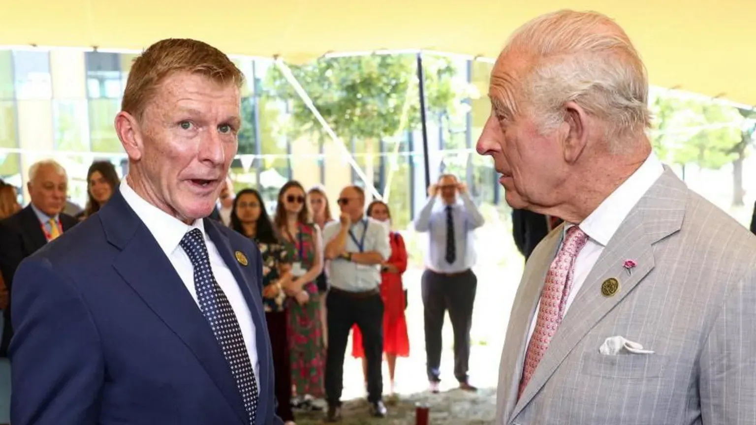 King Charles and astronaut Tim Peake stand next to each other talking, both wearing suits