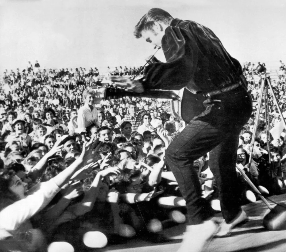 Elvis Presley performing energetically on stage during a live concert in 1956