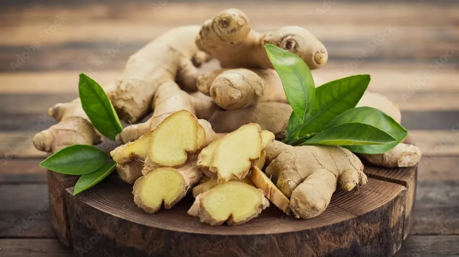 Fresh ginger root with sliced pieces on a wooden surface