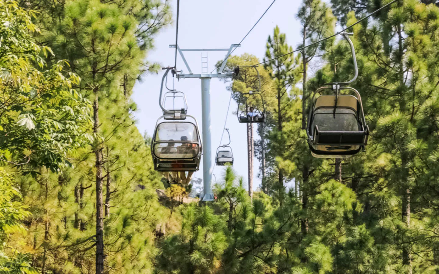 Cable car and chairlift system moving over forested hills in Patriata Murree region