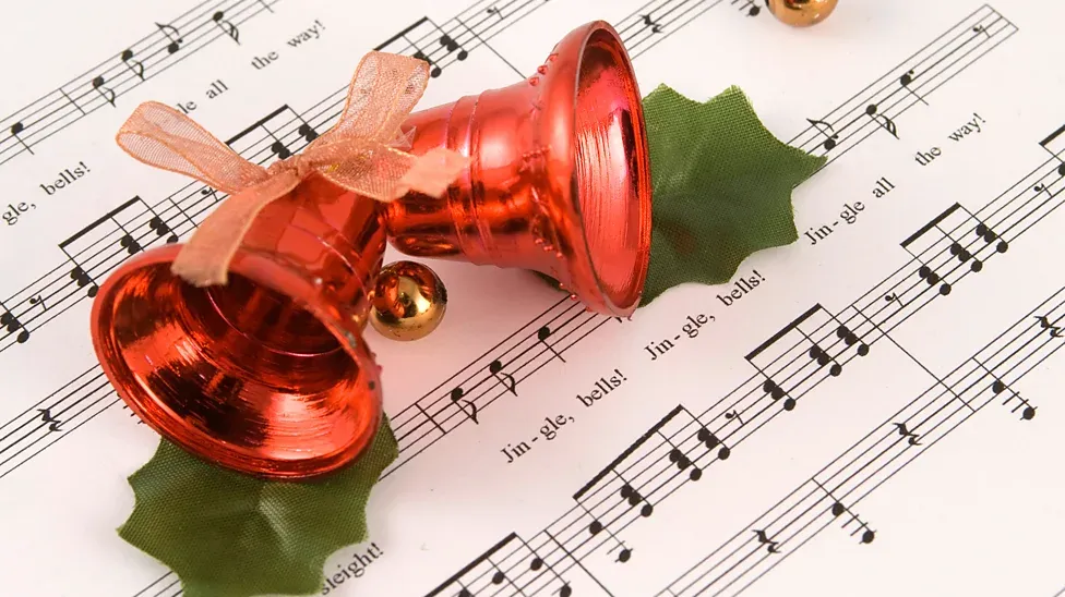 Sheet music for the song Jingle Bells with a pair of bells resting on top