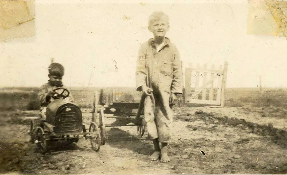 A young boy standing on a farm property in rural West Texas