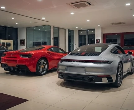 Ferrari 488 GTB and Porsche 911 on display at a luxury used car showroom in Mumbai