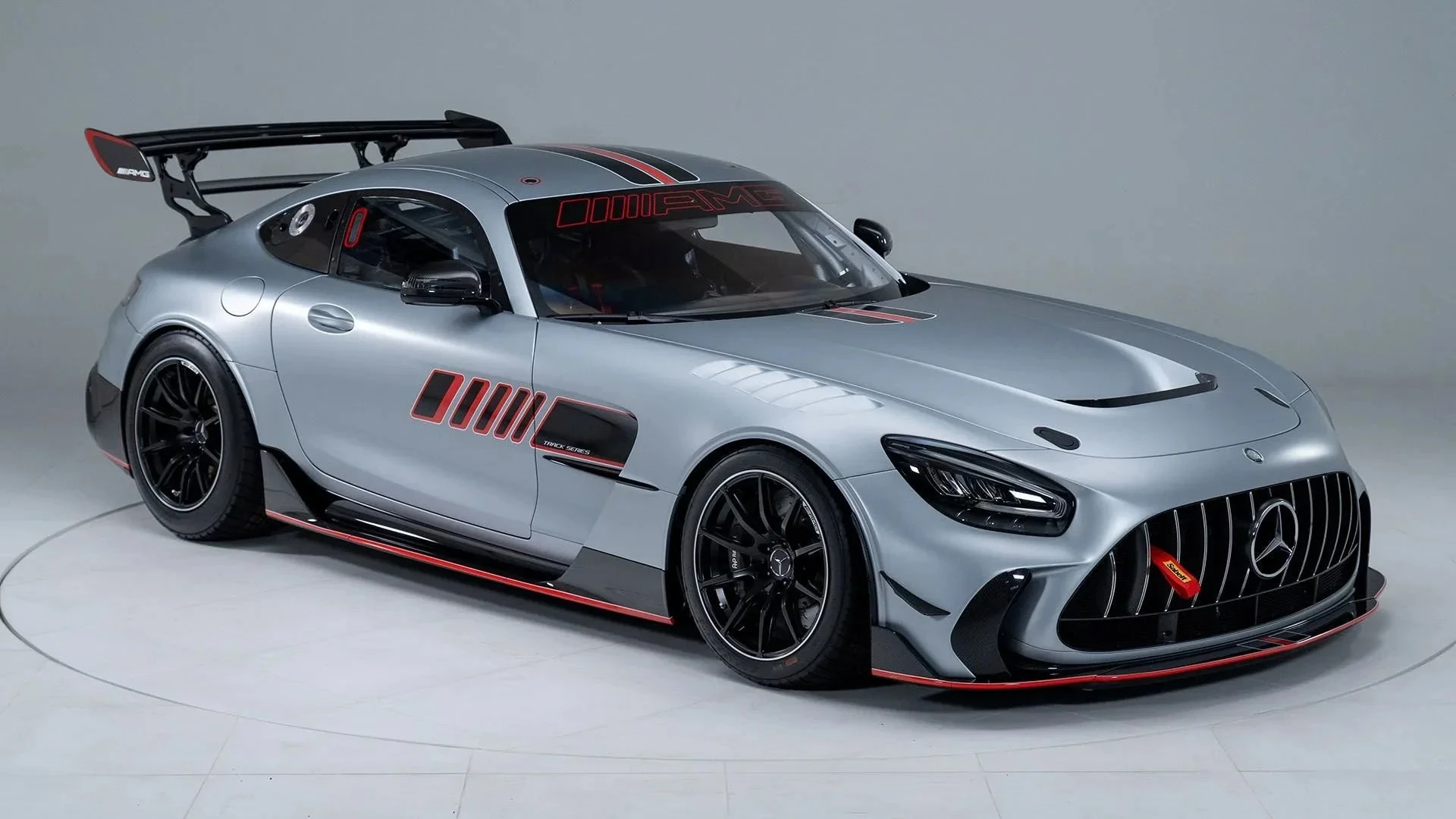 A sleek silver luxury Mercedes vehicle parked in a modern showroom under warm spotlights, representing the highest tier of automotive engineering