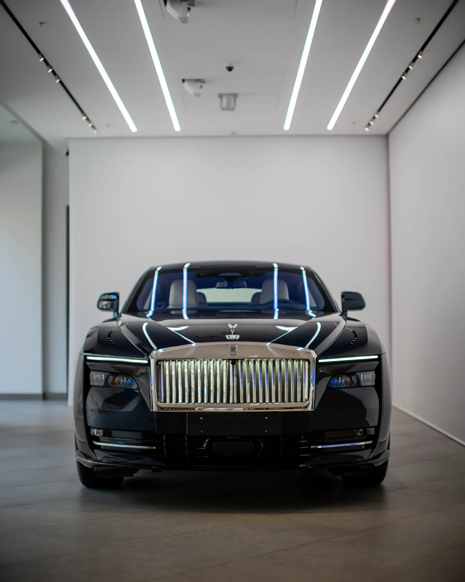 Luxury electric coupe Rolls-Royce Spectre parked in upscale urban setting with charging station visible