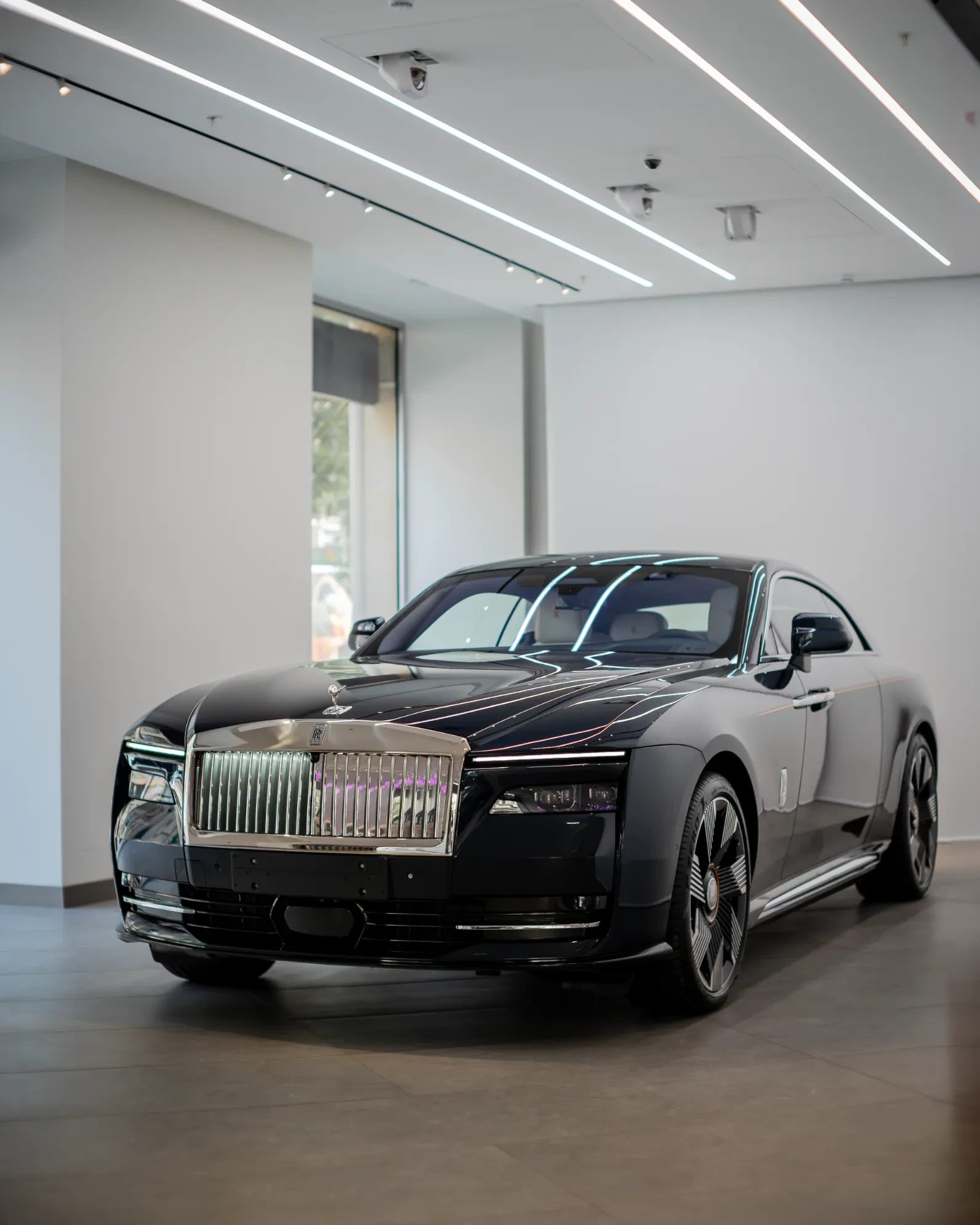 Rolls-Royce Spectre connected to high-power DC fast charger with charging cable plugged into port