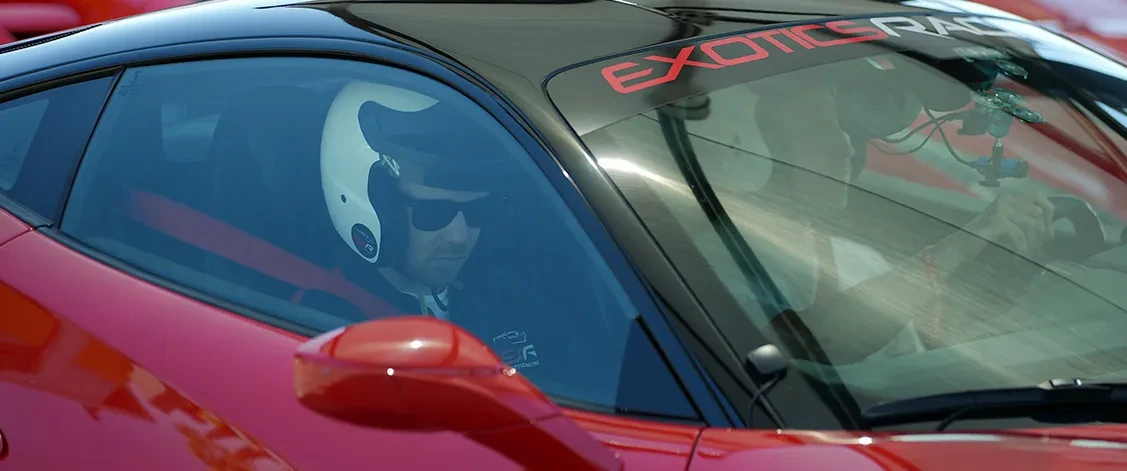 A driver behind the wheel of a two-seat sports car on a winding road